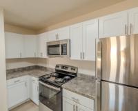 Renovated kitchen featuring white shaker cabinets, stainless steel appliances including refrigerator, oven, and microwave, plus granite-style countertops with ample workspace.
