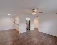 Bright open-concept living space at Huntley Ridge East with wood-style flooring, ceiling fan, neutral walls, and easy flow into the kitchen area.